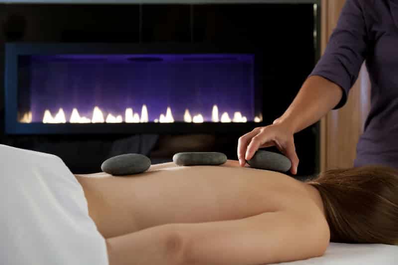 Woman getting a stone massage by a gas fireplace at Herman Hill