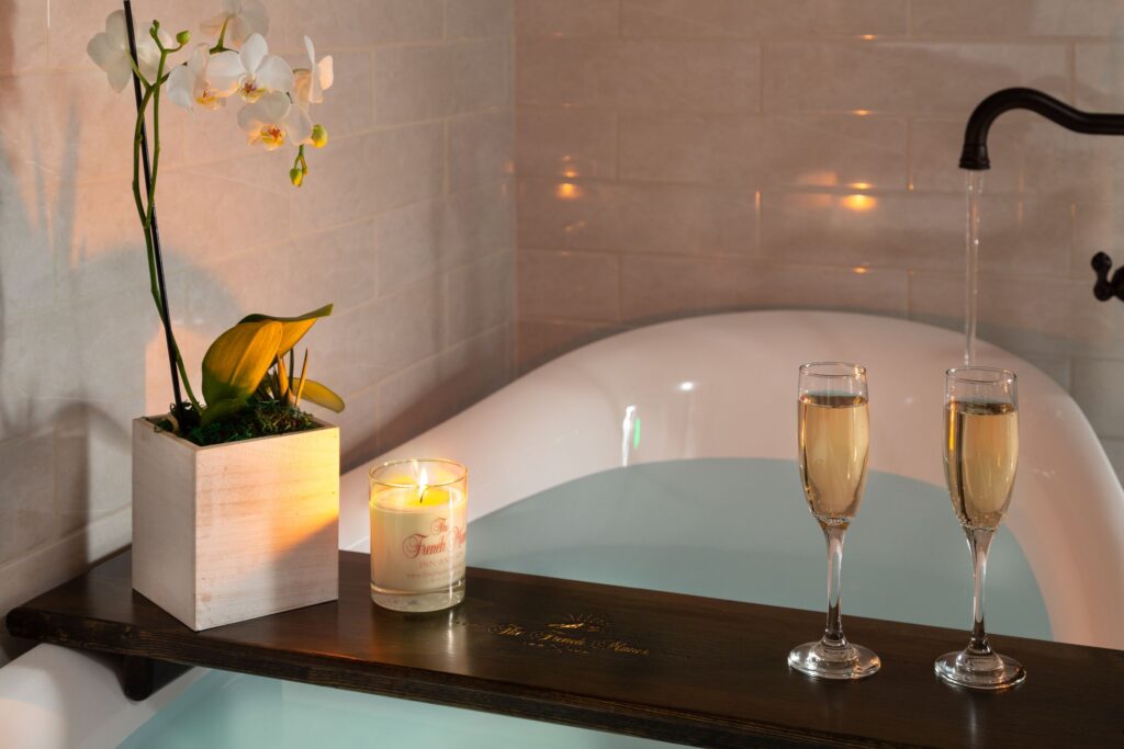 An orchard and champagne sit on the edge of a bathtub