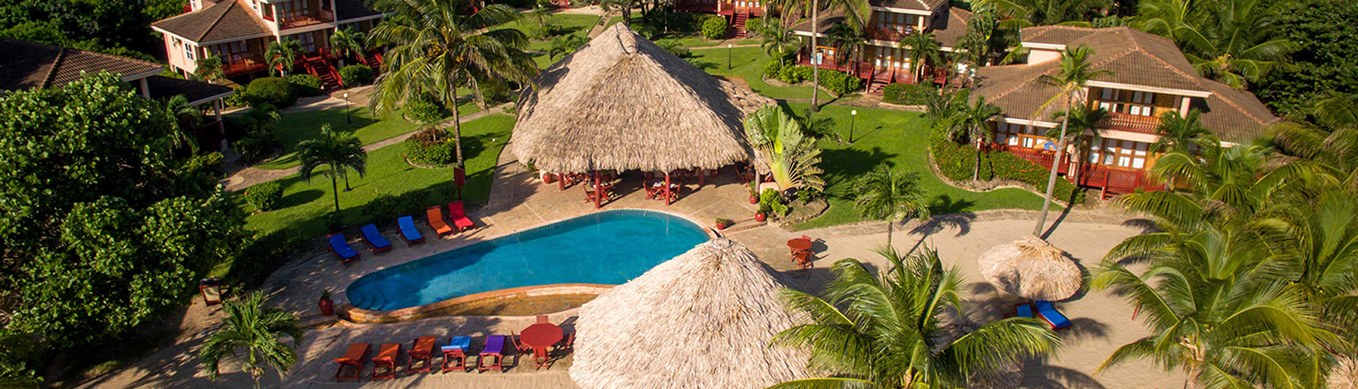 Belizean Dreams swimming pool and thatched-roof resort buildings