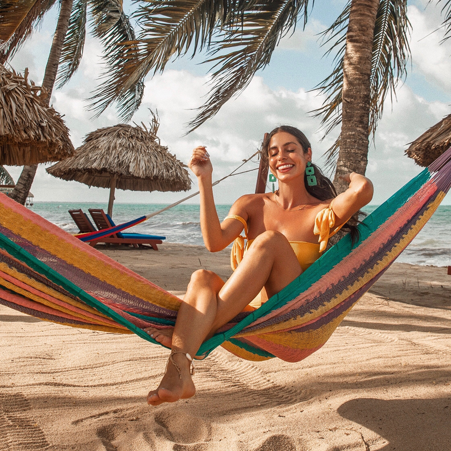 Guest relaxing in a hammock beside the sea at Belizean Dreams