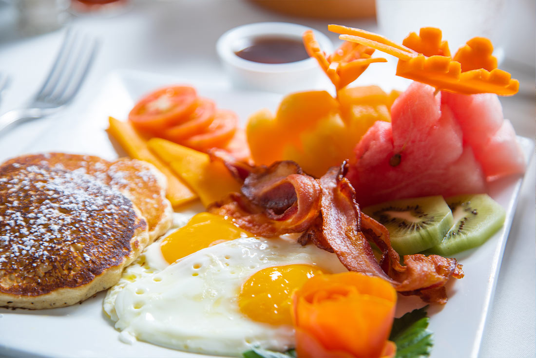 Breakfast plate with pancakes, eggs, bacon and fruit