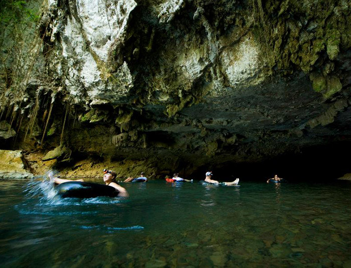 Guests floating through a Belize cave on a guided tubing excursion