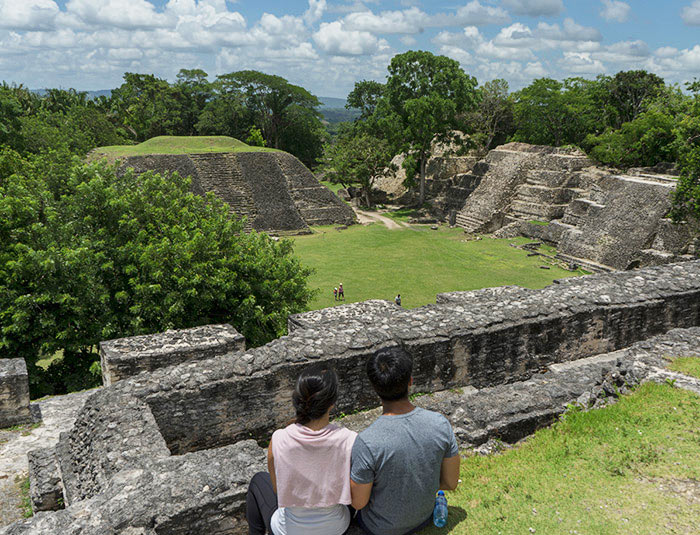 Couple overlooking a Maya archaeological site surrounded by jungle