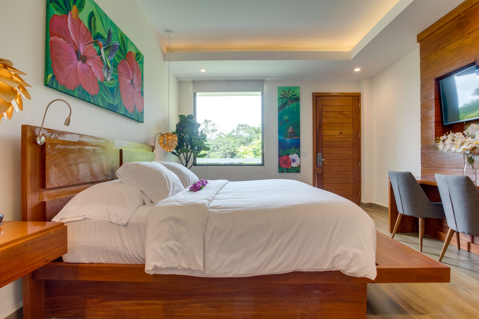 King bedroom with white linens and tropical artwork at Belizean Dreams