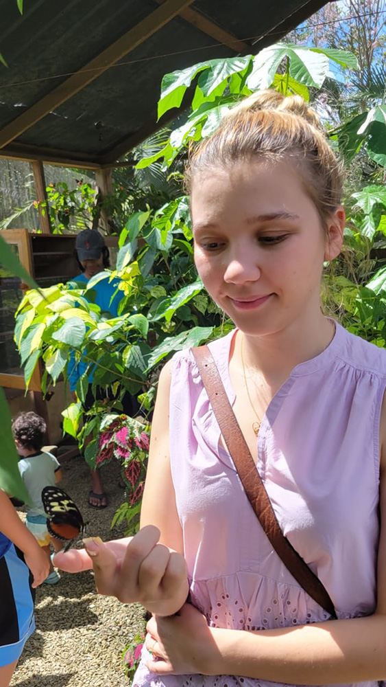 A guest looking at a butterfly perched on her hand during an Eco-Explorer outing
