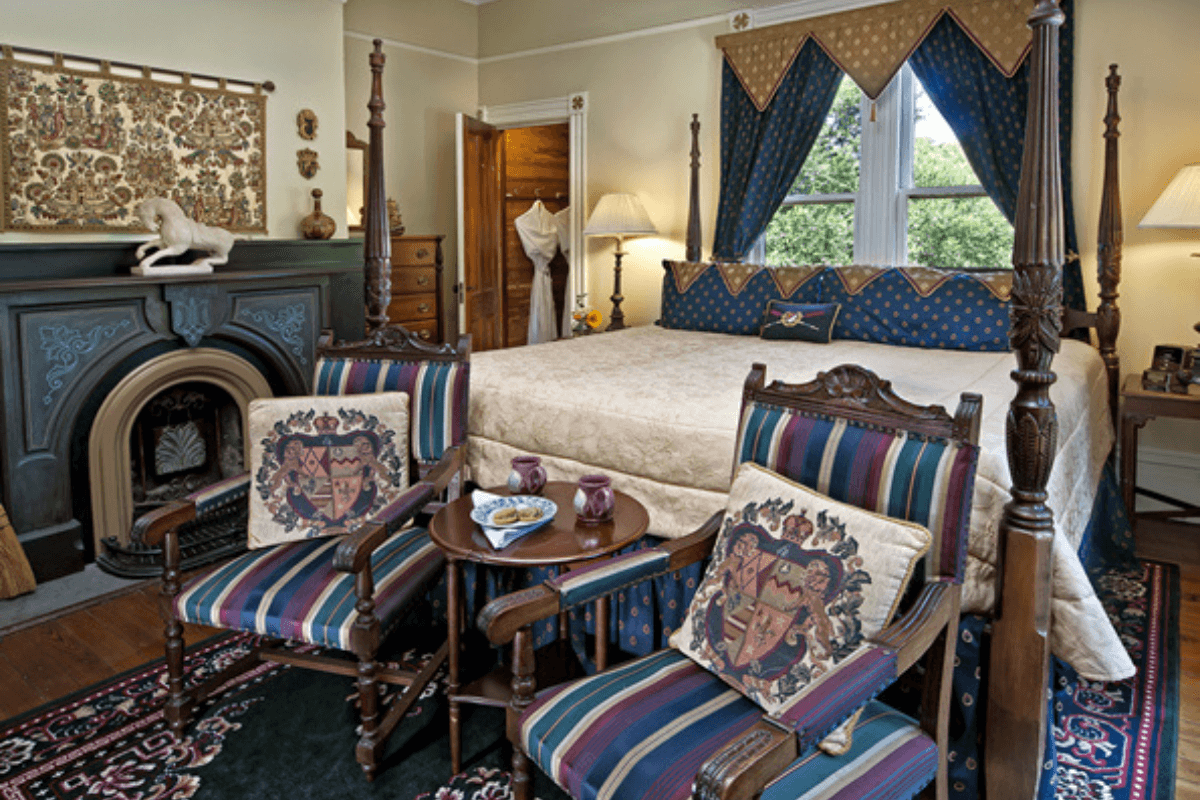 A beautifully decorated bedroom featuring a large bed, two ornate chairs, and elegant furnishings.