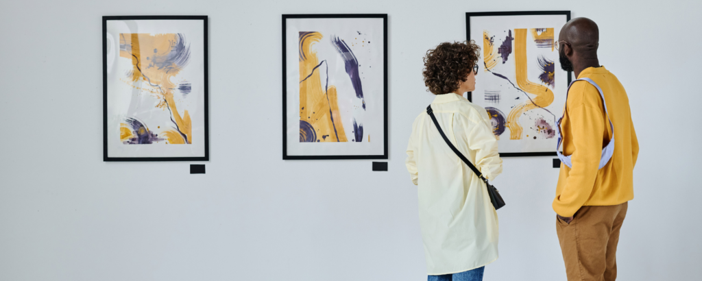 Two people admire abstract paintings displayed in a gallery.