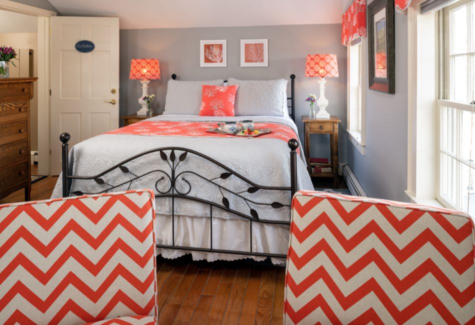 A cozy bedroom featuring a wrought-iron bed with coral accents and chevron-patterned chairs.