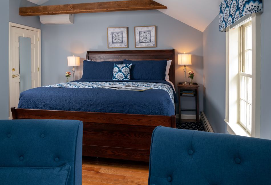 A cozy bedroom featuring a blue-themed bed, wooden furniture, and soft lighting.