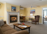 Cozy living room featuring a fireplace, a wooden coffee table with apples and a book, and comfortable seating.