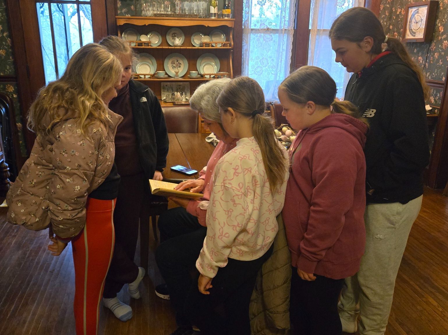 Grandmother and granddaughters gathered around a Whispering Pines guest journal, reading an entry their family left six years earlier.