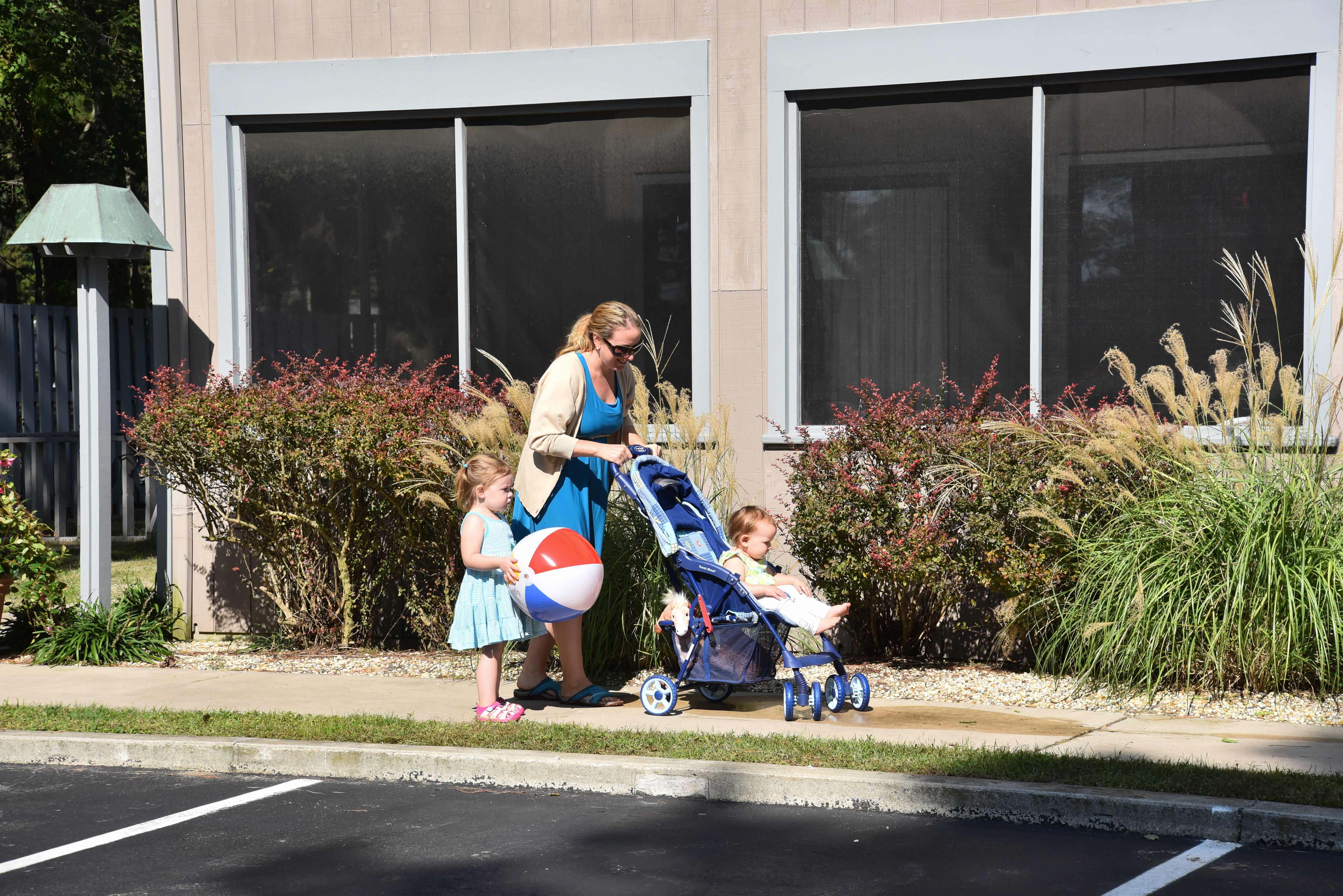 A mother and her two young daughters heading out past the rooms at the Refuge Inn, one of them carrying a beach ball.