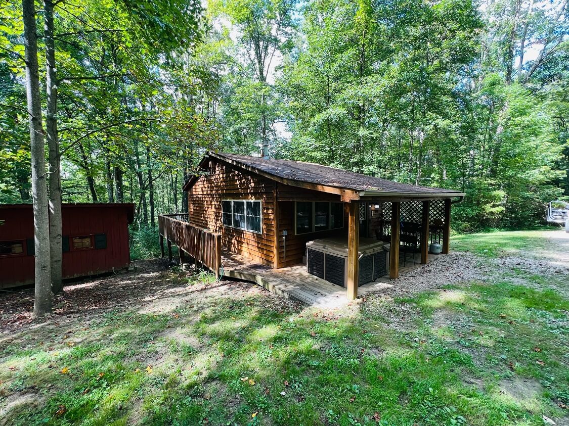 A rustic cabin surrounded by trees in a wooded area.
