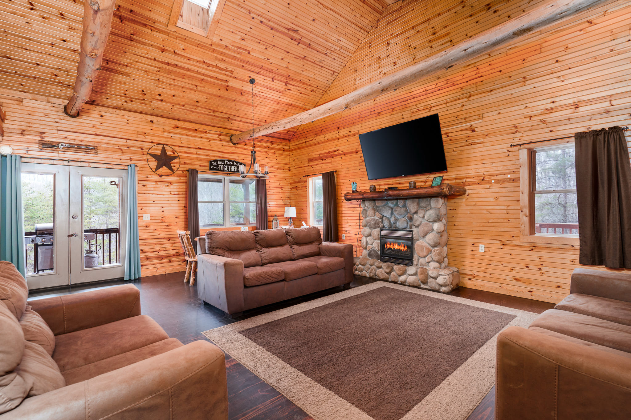 Cozy wooden living room with a stone fireplace, large TV, and comfortable seating.
