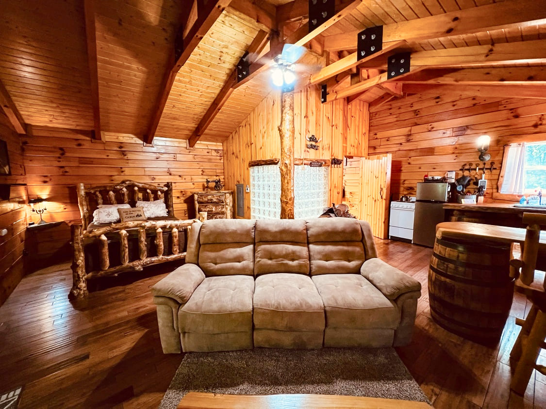 Cozy wooden cabin interior featuring a sofa, rustic decorations, and a warm ambiance.