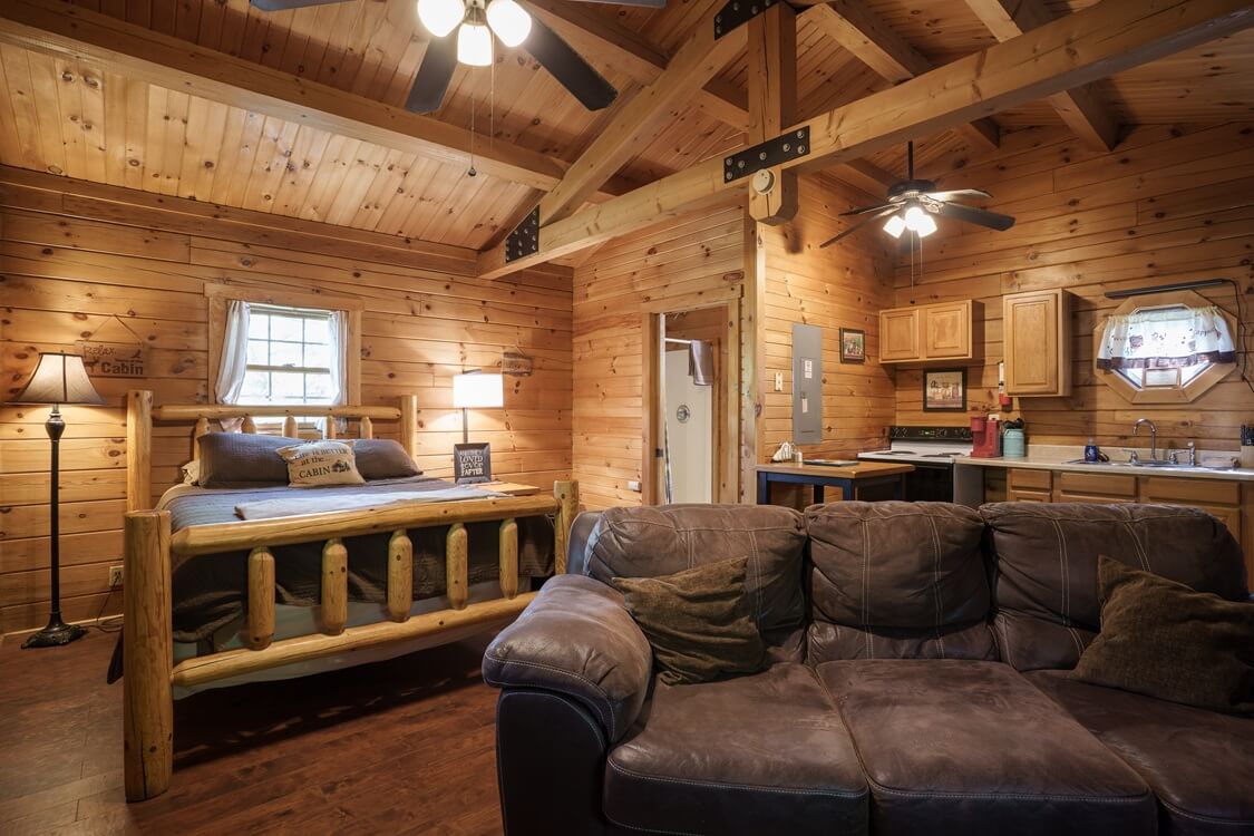 A cozy wooden cabin interior featuring a kitchen area, dining table, and seating.