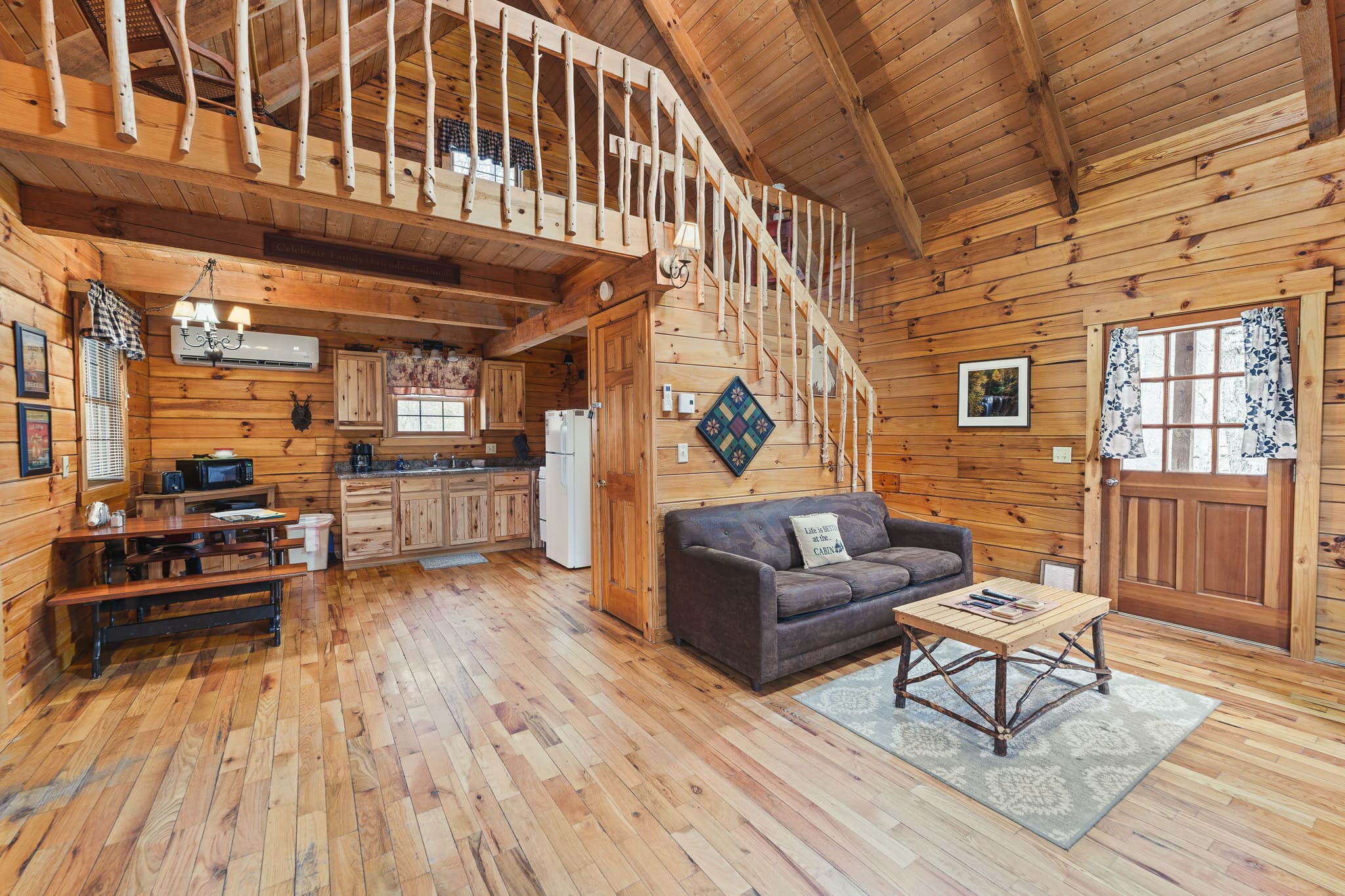 Interior of a cozy wooden cabin featuring a living area, kitchen, and staircase.