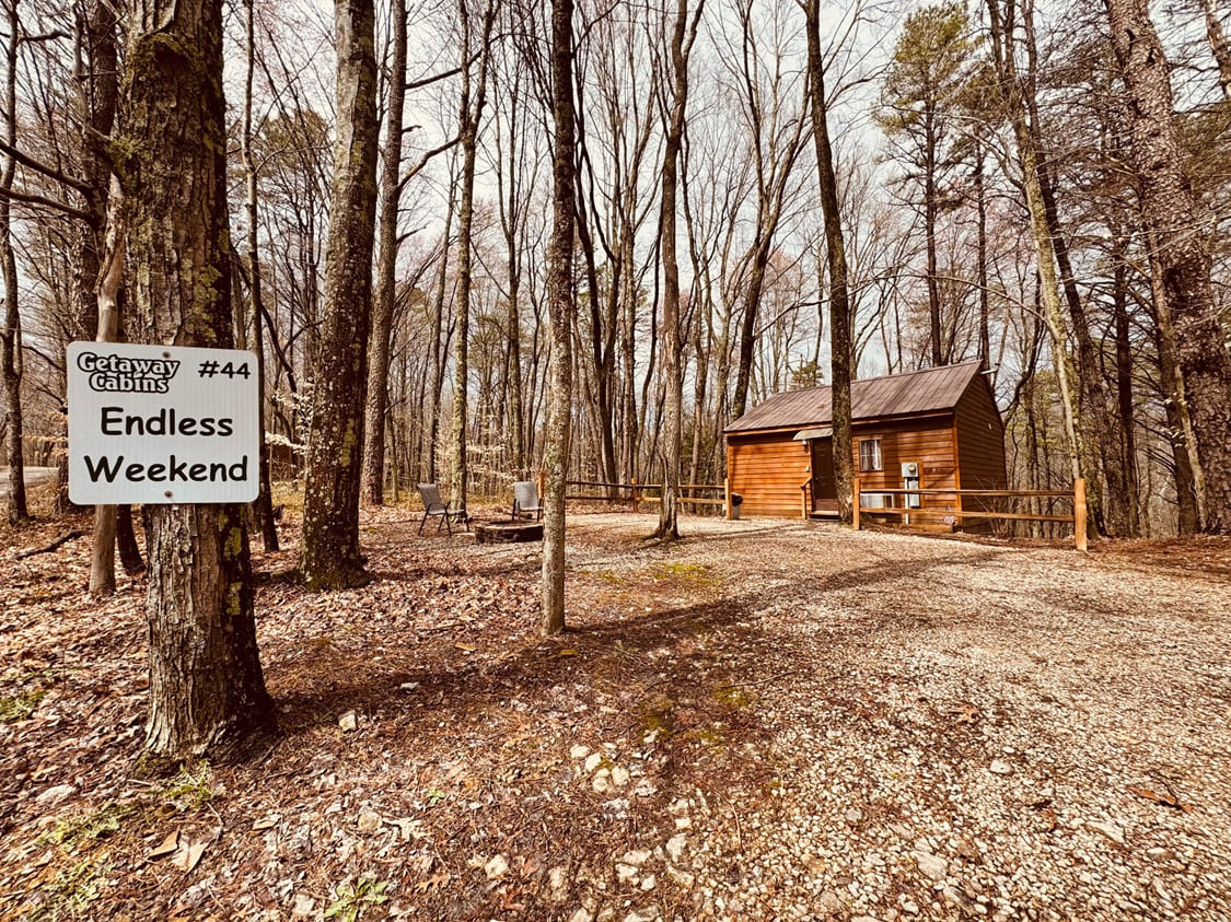 A cozy cabin nestled in a wooded area with a sign that reads Getaway Cabins 44 Endless Weekend.