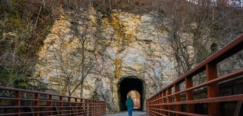 A man walking through an old tunnel that runs through a Missouri river bluff