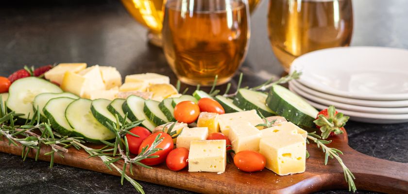 Charcuterie board with cheese, cucumbers, tomatoes, and rosemary served with iced tea at Honeys Farmhouse.