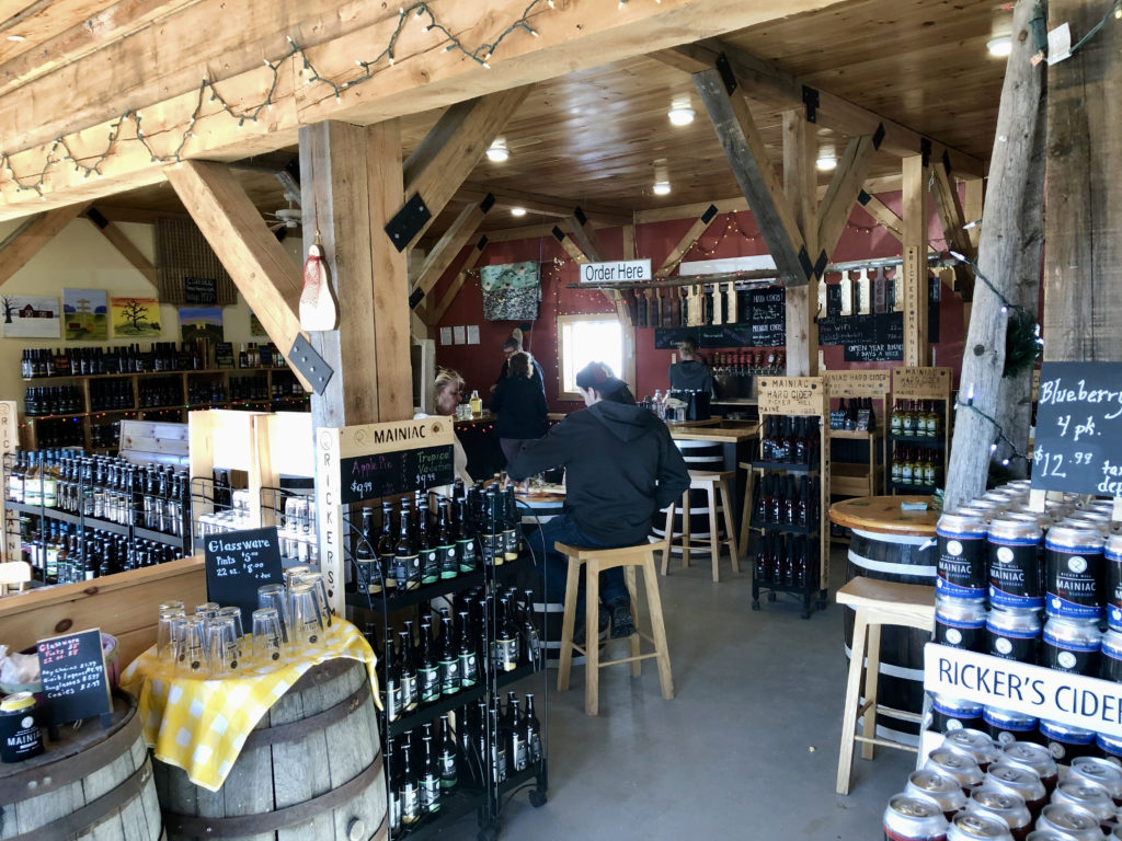Interior of a tasting room with barrels, bottles, and cans under a wood timbered ceiling