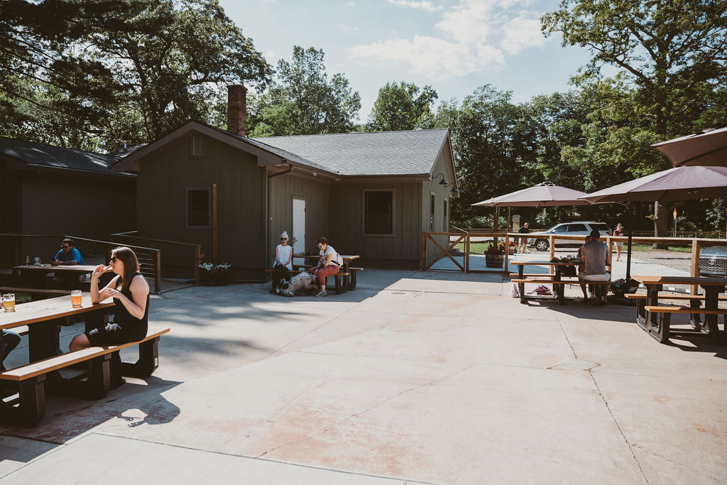 View of Seedz patio with people sitting at various picnic tables shaded by umbrellas