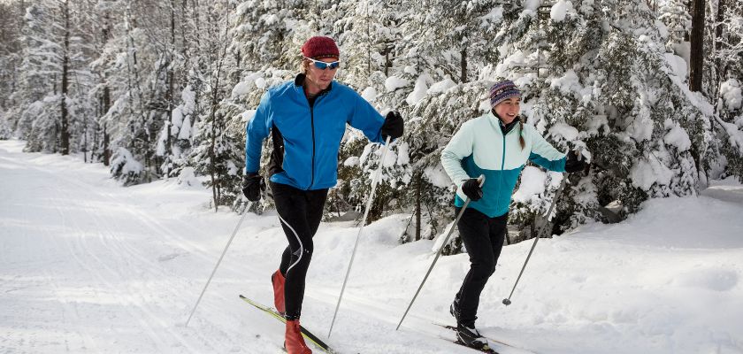 romantic couple cross-country skiing on a tree-lined trail