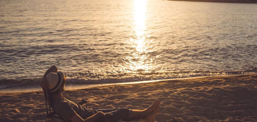man relaxing on the beach at sunset